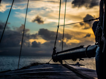 Man fishing on sea against sky during sunset