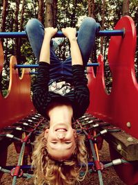Portrait of happy cute girl playing on monkey bars in playground