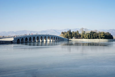 Arch bridge over river against clear sky