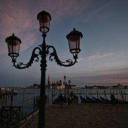 Street light by sea against sky during sunset