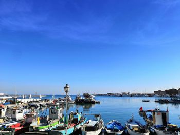 Sailboats moored at harbor against blue sky