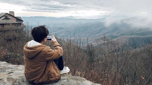 Rear view of woman photographing on mountain