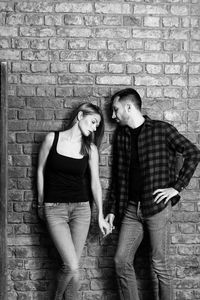 Young couple standing against brick wall