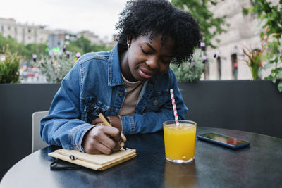 Mid adult woman holding drink sitting on table