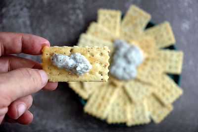 Close-up of hand holding cracker with pate
