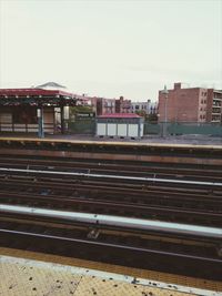 Railroad tracks in city against clear sky