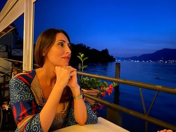 Side view of young woman sitting on railing