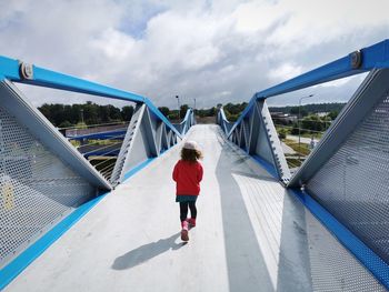 Rear view of girl on bridge against sky