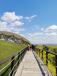 Footbridge on footpath against sky