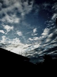 Low angle view of power lines against cloudy sky