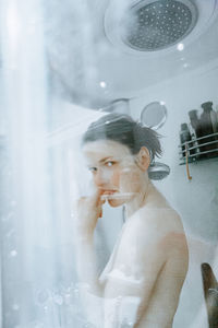 Portrait of woman looking through glass window