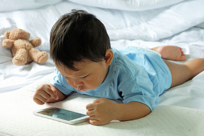 Rear view of boy lying on bed at home