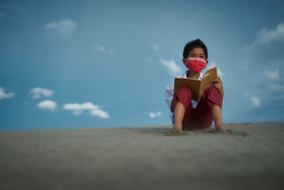 Side view of young man standing against sky