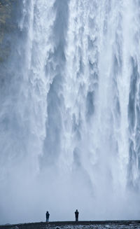 Young couple looking at skógafoss waterfall in south iceland