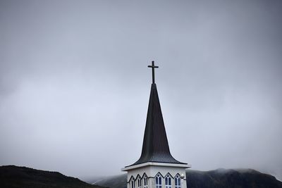 Low angle view of cross on building against sky