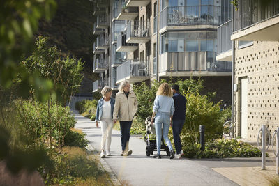 Senior and young couple with baby stroller walking in residential area