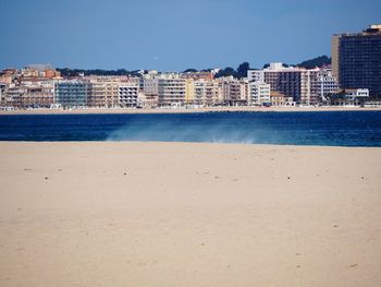 Sea by cityscape against clear sky