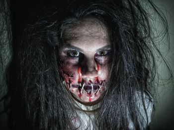 Close-up portrait of woman with spooky halloween make-up by wall