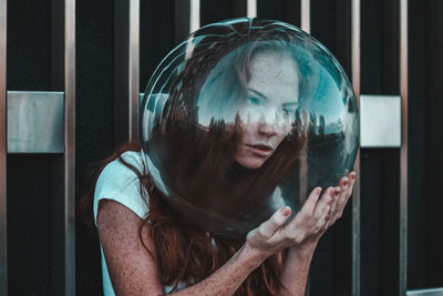 Close-up of thoughtful young woman wearing glass helmet in head against metallic railing