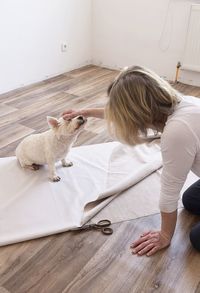 Rear view of woman with cat sitting on wooden floor at home