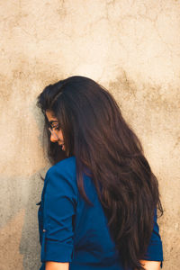 Side view of woman standing against wall