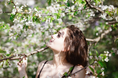 Young woman amidst flowering tree