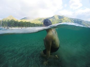 Man swimming in sea against sky