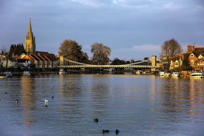 Scenic view of river by buildings against sky