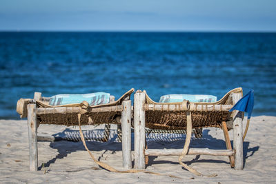 Camp beds on beach against clear blue sky