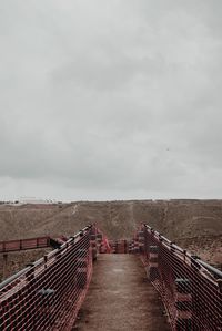 Empty footbridge against sky