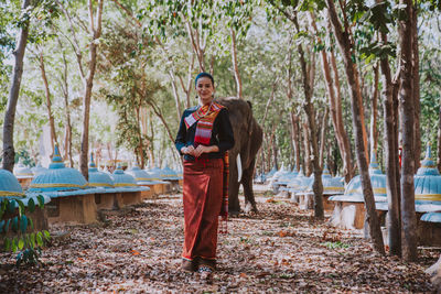 Portrait of smiling woman standing with elephant in temple