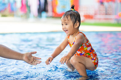 Cute girl crouching in swimming pool at water park