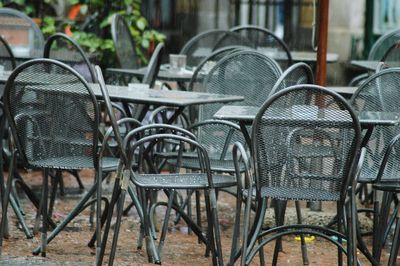 Empty chairs and tables at sidewalk cafe against building