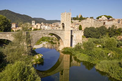 Arch bridge over buildings against sky