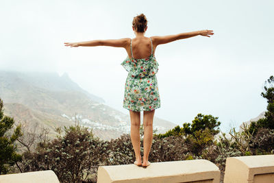 Rear view of young woman standing against sky