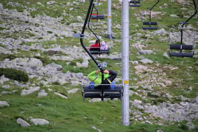 Rear view of people on ski lifts grassy landscape