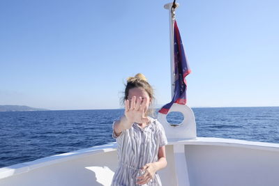 Teenage girl showing stop sign while standing in boat