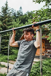 Young man doing pull-ups on pull-up horizontal bar during his calisthenics workout outdoors