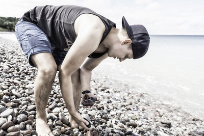 Man collecting pebbles on shore