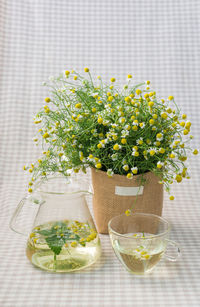 Close-up of flowers with jar and cup