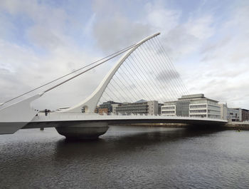 Bridge over river against sky in city