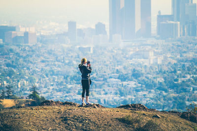 Woman photographing cityscape against sky
