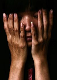 Close-up of young woman touching her face in dark