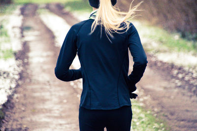 Rear view of woman jogging on road amidst trees