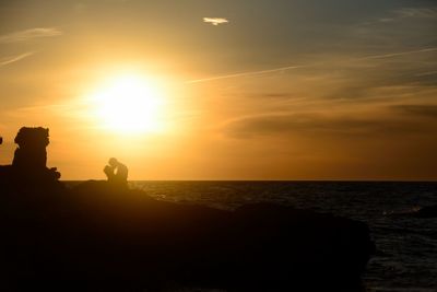 Silhouette man by sea against sky during sunset