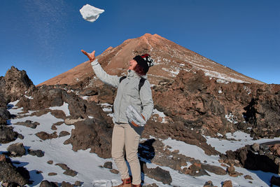 Woman standing on rock against sky during winter