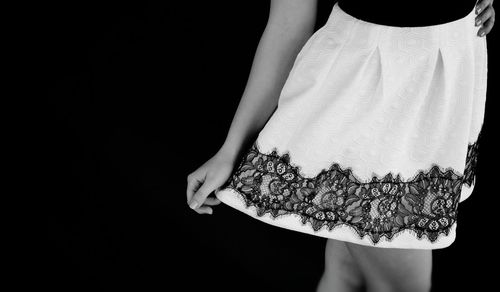 Midsection of woman wearing mini skirt against black background