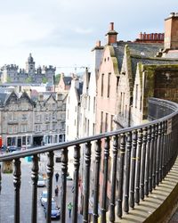 Bridge over river amidst buildings in city against sky