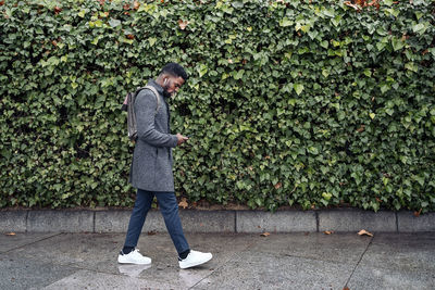 Side view of man walking on footpath against plants