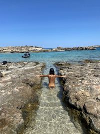 Rear view of man on beach against clear sky